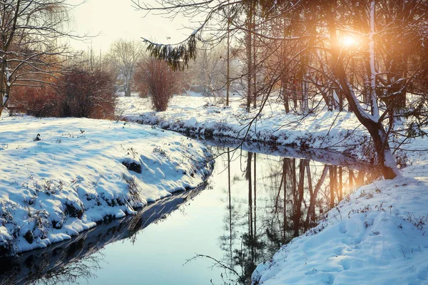 Paisagem de inverno por um rio durante o pôr do sol — Fotografia de Stock