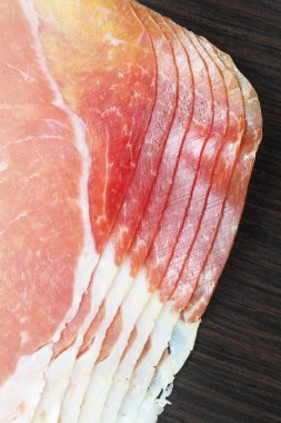 Jamon (hamon) veya prosciutto ahşap bir arka plan üzerine dilimlenmiş