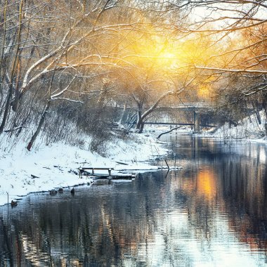 Gün batımında nehir kıyısında kış manzarası