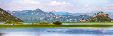 Güneşli bir günde Skadar Gölü 'nün yeşil dağ tepeleriyle çevrili muhteşem manzarası. Konum: Ulusal park Skadar Gölü, Karadağ, Balkanlar, Avrupa.