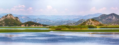 Güneşli bir günde Skadar Gölü 'nün yeşil dağ tepeleriyle çevrili muhteşem manzarası. Konum: Ulusal park Skadar Gölü, Karadağ, Balkanlar, Avrupa.