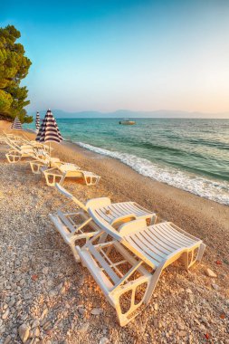 Günbatımında Makarska Riviera 'nın Gradac plajında güneş pansiyonları ve plaj şemsiyeleri. Konum: Gradac, Makarska riviera, Dalmaçya, Hırvatistan, Avrupa