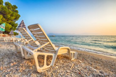 Günbatımında Makarska Riviera 'nın Gradac plajında güneş pansiyonları ve plaj şemsiyeleri. Konum: Gradac, Makarska riviera, Dalmaçya, Hırvatistan, Avrupa