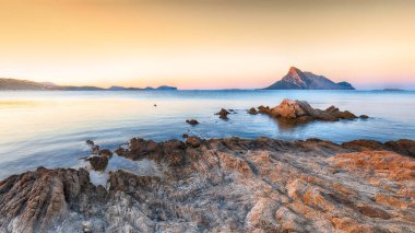 Gök mavisi suyun üzerinde gün batımı için harika bir zaman Porto Taverna sahilinde kayalar var.