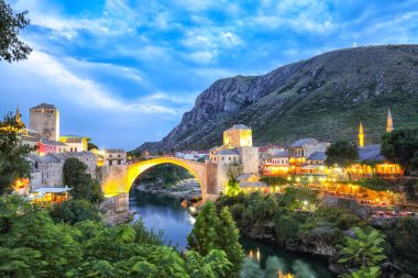 Akşamları Mostar Köprüsü, evler ve minarelerle Mostar 'ın görkemli akşam manzarası. Konum: Mostar, Old Town, Bosna-Hersek, Avrupa