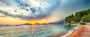 Adriyatik kıyısının Budva yakınlarındaki Sveti Stefan plajındaki fantastik günbatımı manzarası. Konum: Budva Riviera, Karadağ, Adriyatik denizi, Avrupa