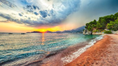 Adriyatik kıyısının Budva yakınlarındaki Sveti Stefan plajındaki fantastik günbatımı manzarası. Konum: Budva Riviera, Karadağ, Adriyatik denizi, Avrupa