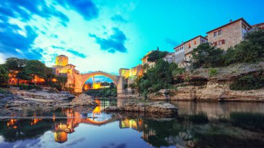 Akşamları Mostar Köprüsü, evler ve minarelerle Mostar 'ın görkemli akşam manzarası. Konum: Mostar, Old Town, Bosna-Hersek, Avrupa