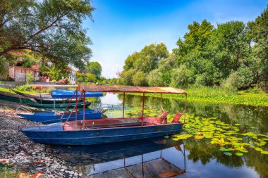 İskeledeki sazdan çatılı teknelerin manzarası. Skadar göl turu. Konum: Skadar Gölü Ulusal Parkı, Karadağ, Balkanlar, Avrupa.