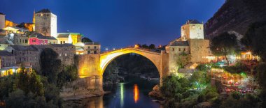Akşamları Mostar Köprüsü, evler ve minarelerle Mostar 'ın görkemli akşam manzarası. Konum: Mostar, Old Town, Bosna-Hersek, Avrupa