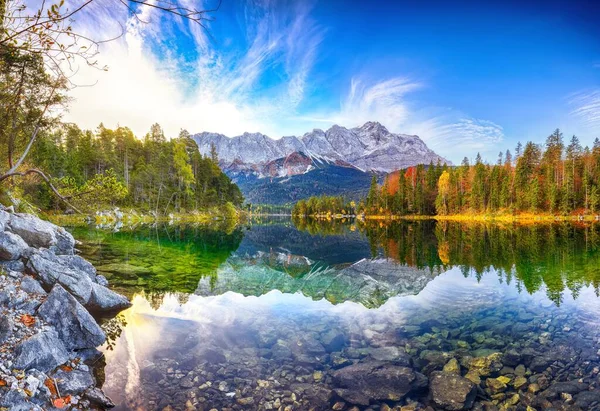 Zugspitze Zirvesi 'nin önündeki Eibsee Gölü' nün sonbahar manzarası güneş ışığı altında.