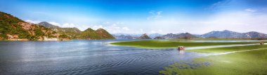 Güneşli bir günde Skadar Gölü 'nün yeşil dağ tepeleriyle çevrili muhteşem manzarası. Konum: Ulusal park Skadar Gölü, Karadağ, Balkanlar, Avrupa.