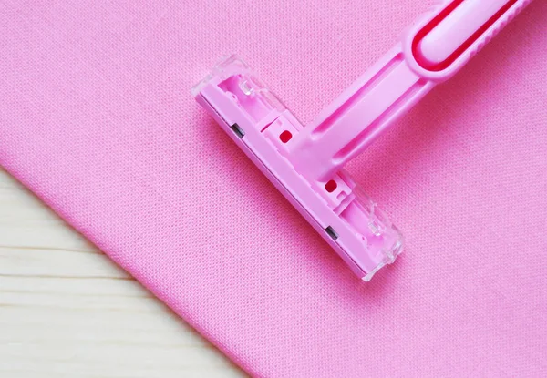 Close up women's disposable razor on pink background.