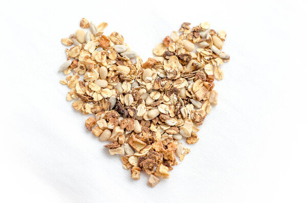 Вид сверху завтрак из домашней зерновой крупы с орехами и фруктами, в форме сердца на белом фоне. Здоровое питание, диета, детоксикация, чистое питание, вегетарианская концепция
.