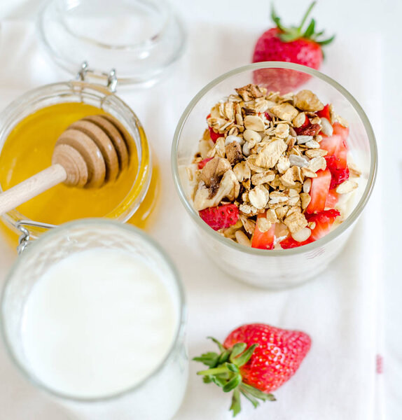 Здоровый завтрак из домашней мюсли с клубникой, орехами и фруктами, мёд с более дождливым фоном. Утренняя еда, диета, детоксикация, чистое питание, вегетарианская концепция
.