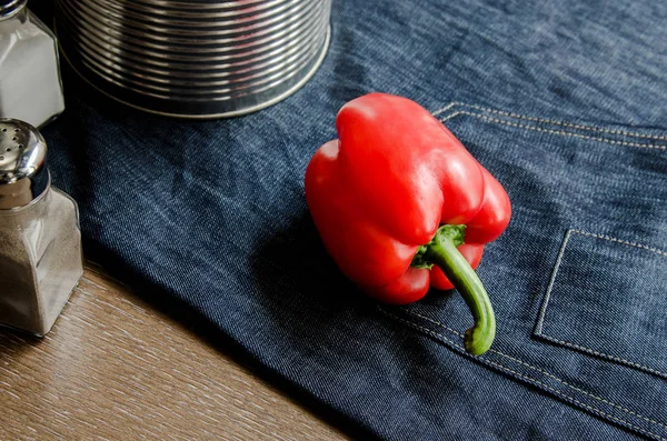 Peperone bulgaro sul tavolo da pranzo, grembiule blu, posate, pentola di ferro. verdure, concetto di cucina casalinga Fotografia Stock