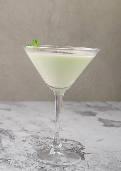 Tampilan teratas koktail susu krim dengan mint pada latar belakang abu-abu. Sebuah irish cream liquor dalam gelas martini. Menu minuman beralkohol batang Stok Foto