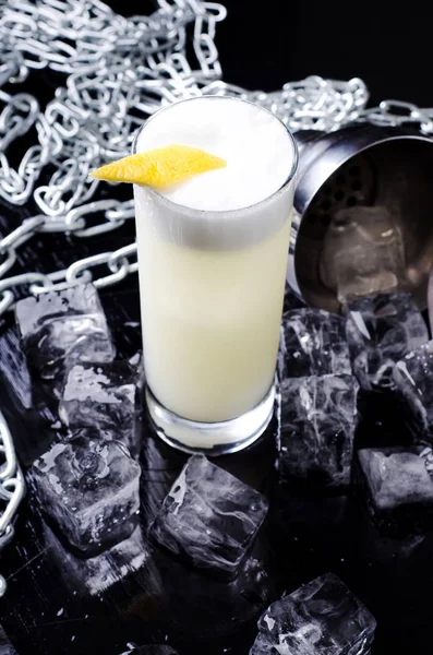 Cocktail alcolico - bevanda Yellow Bird con fetta di limone in un bicchiere con cubetto di ghiaccio in shaker su un ristorante di sfondo nero. Barra dell'alcool, spazio di copia . — Foto Stock