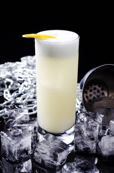 Cocktail alcolico - bevanda Yellow Bird con fetta di limone in un bicchiere con cubetto di ghiaccio in shaker su un ristorante di sfondo nero. Barra dell'alcool, spazio di copia . — Foto Stock