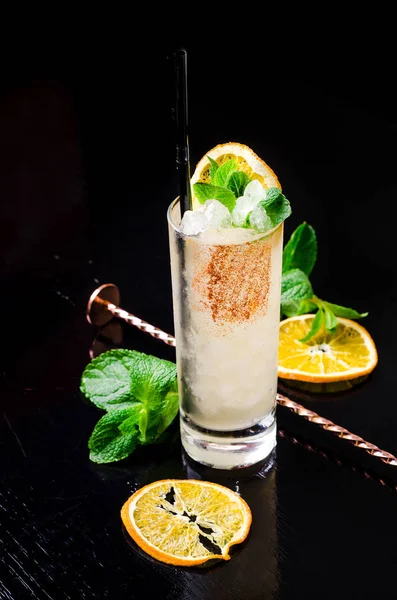 Alkollü kokteyl - sarı portakal suyu bir bardak nane küp buz shaker bir siyah arka plan restoran ile dilim limon, yeşil. Alkol, kopya alanı.