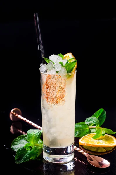 Cocktail alcolico - Orange drink giallo con fetta di limone, menta verde in un bicchiere con cubetto di ghiaccio in shaker su un ristorante di sfondo nero. Barra dell'alcool, spazio di copia . — Foto Stock