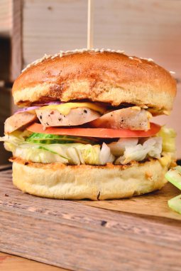 Üstten Görünüm taze ev yapımı hamburger tavuk, salata, peynir, soğan, salatalık, domates, sause ve karanlık bira ile ahşap bir masa, tablo arka plan üzerinde. Juicey gurme rulo ekmek, lokanta kavramı. Metin yer