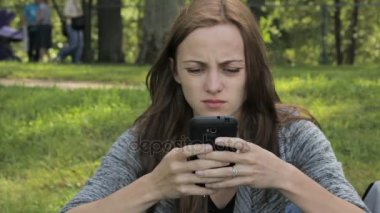 Kadın parkta bir smartphone içinde sosyal ağlarda iletişim kurar