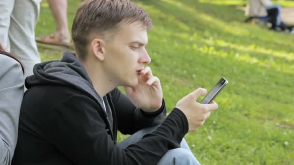 Hombre buscando información sobre un smartphone en el parque — Vídeos de Stock