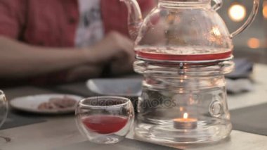İnsanlar kafe, ısıtmalı mumlar bir masada şeffaf çaydanlık