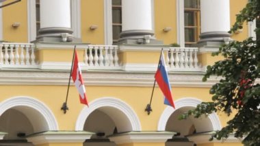 Bir bina rüzgarda Rus ve Kanada bayrağı tasa