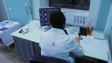 Kadın doktor hastanede tomografi monitörde görünüyor.
