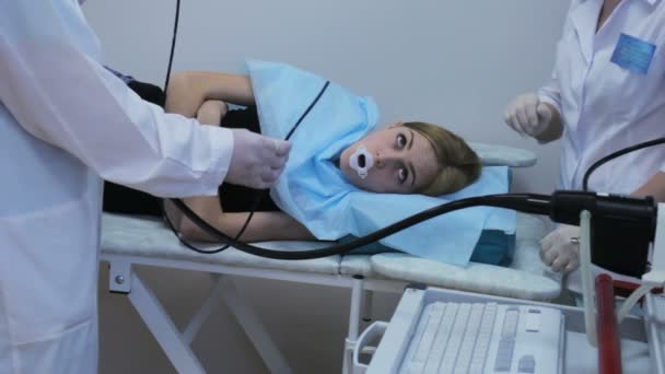 Доктор делает эндоскопию через рот молодой девушки, вытаскивает трубчатый гастроскоп — стоковое видео