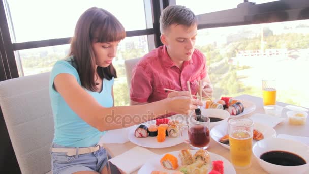 Jeune couple manger des rouleaux avec des baguettes, nourriture asiatique — Video