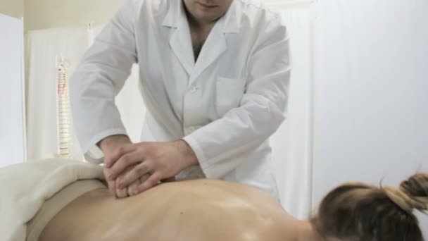 Jovem recebe uma massagem de cura das costas e coluna vertebral no salão — Vídeo de Stock