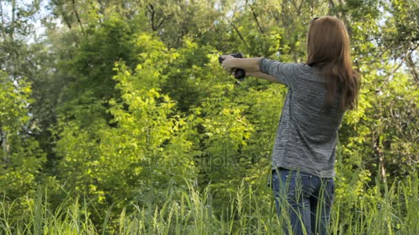 Девушка стреляет из пистолета в природу — стоковое видео