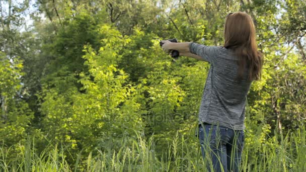 Chica dispara un arma en la naturaleza — Vídeos de Stock