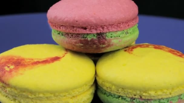 Macaron rosa, giallo e verde ruotano rapidamente uno sfondo scuro — Video Stock