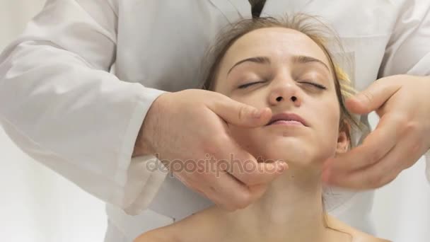 Massage du menton et du visage d'une jeune femme, mains d'un masseur — Video