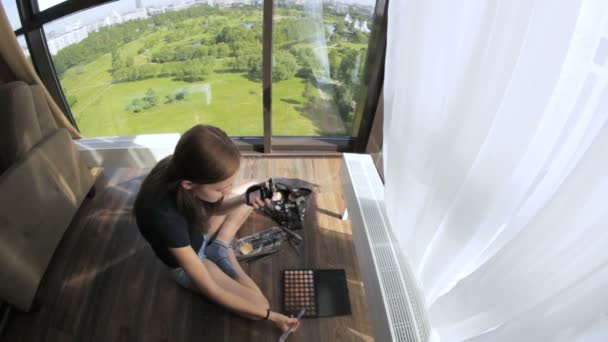 Schönes Mädchen macht Make-up, farbige Augen, Panoramafenster — Stockvideo