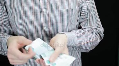 Bir adam para sayar, bu kıvrımlar ve cebine koyar