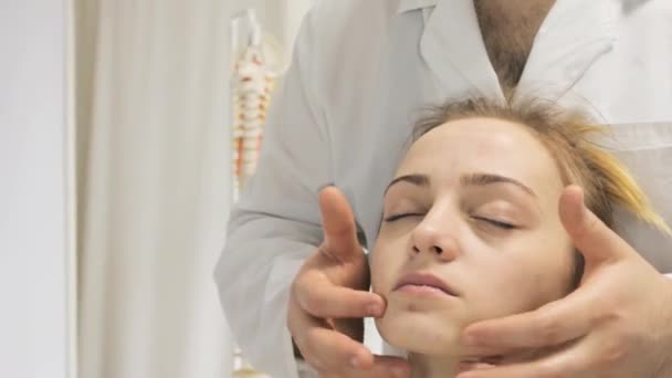 Doctor massages the face of a young girl with her fingers — Stock Video