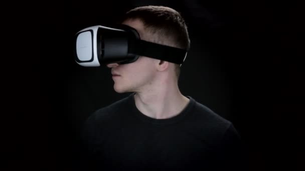 Joven sobre fondo negro con gafas de realidad virtual — Vídeo de stock