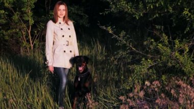 Genç bir kızın yanında oturan Doberman