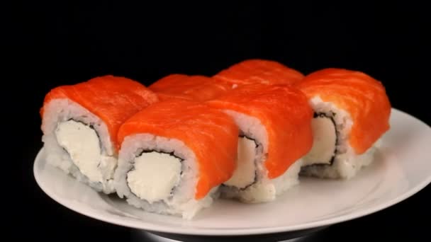 Philadelphia rolls are rotating on a plate, Japanese cuisine on black background — Stock Video
