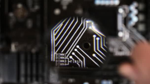 The master looks a components at motherboard under a magnifying glass — Stock Video