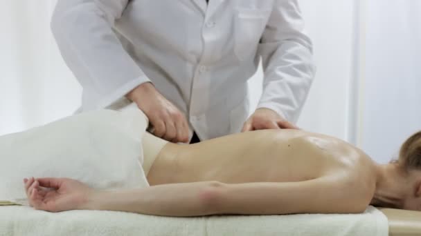 Доктор массажист массирует спину молодой девушке — стоковое видео