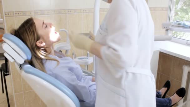 Дантист проверяет рот молодой девушки с помощью инструментов — стоковое видео