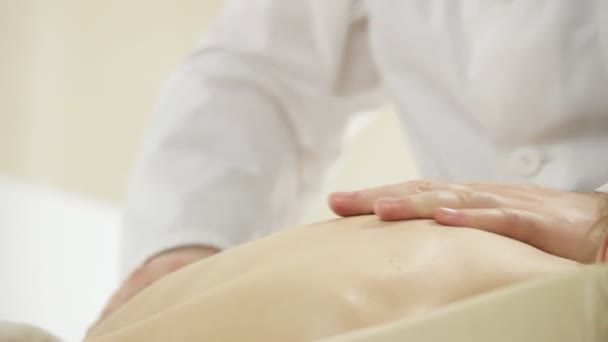 Doutor massagista fazendo massagem no ombro, uma jovem deitada em um sofá, a panela da câmera — Vídeo de Stock