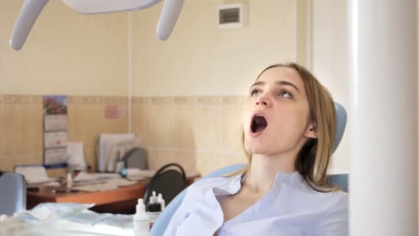 Flickan i tandläkare stol öppnade munnen, läkaren justerar ljus — Stockvideo