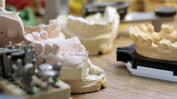 Desk prosthetist, a lot of models of dental jaw prostheses — Stock Video